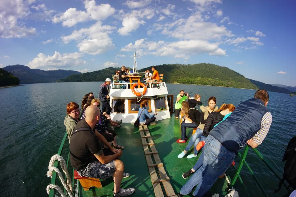 Bloggers on the deck of a boat on a lake between forested hills